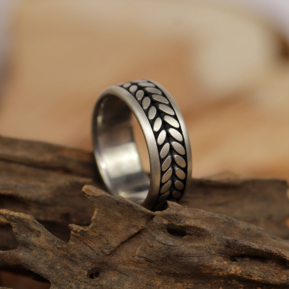 Macro photography highlighting the nature-inspired engraving on the silver band.